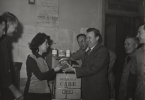 Distribution of CARE packages by Walter Reuther, President of the U.A.W. - C.I.O. at the Headquarters of F.O. Union of automobile workers of the Renault plant in Paris, on December 12, 1949. -The picture shows Walter Reuther presenting one of the CARE packages to shop steward Mlle.Lucie Engler, surrounded by other shop stewards and Daniel Benedict, Chief of Care Mission/France.